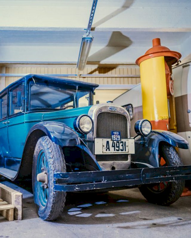Vanha sininen saksalainen auto 20-luvulta ja vanha Esson bensatankki