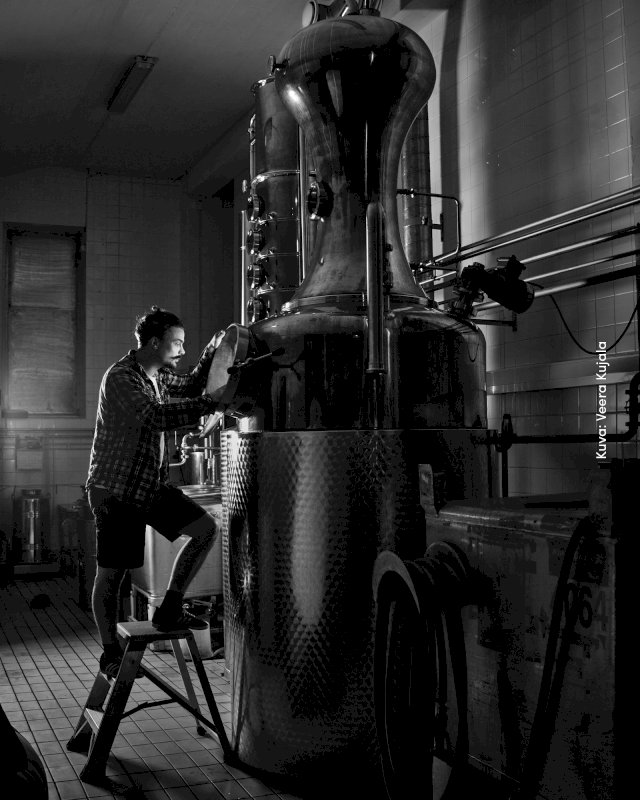 Kyrö Distilleryn tislaamo ja mies jakkaralla