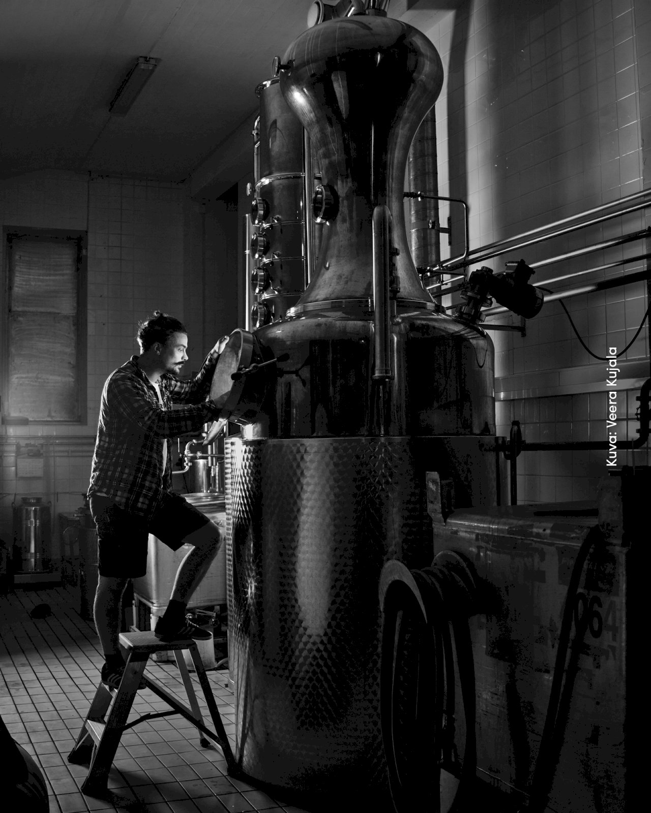 Kyrö Distilleryn tislaamo ja mies jakkaralla