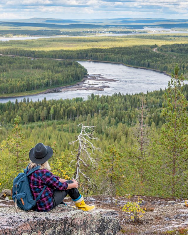 Retkeilijä korkealla kalliolla Väylänvarren maisemien auetessa alla